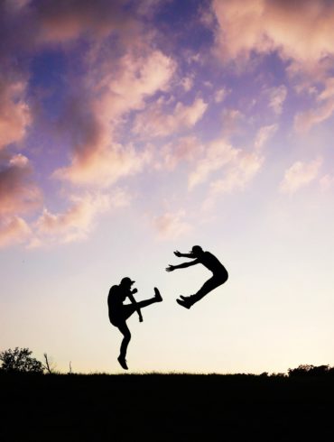 two people fighting as the sun is setting